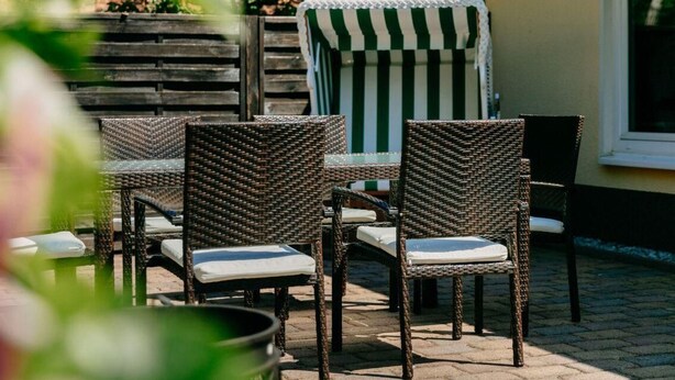 Ein Patio mit Korbmöbeln und einem gestreiften Stuhl.