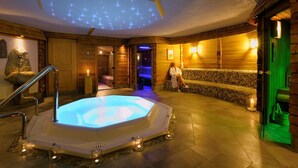 Ein Wellnessbereich mit Whirlpool, Holzwänden und einer Deckenleuchte.