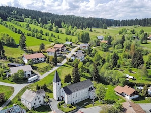 Un village avec une église, des immeubles d’habitation et des champs verdoyants.