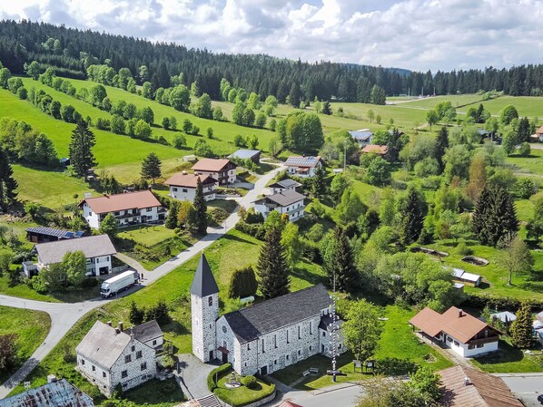Un village avec une église, des immeubles d’habitation et des champs verdoyants.