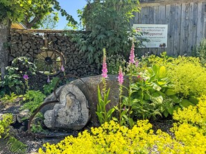 Ein Garten mit Holzzaun, Steinmauer und einem Schild.