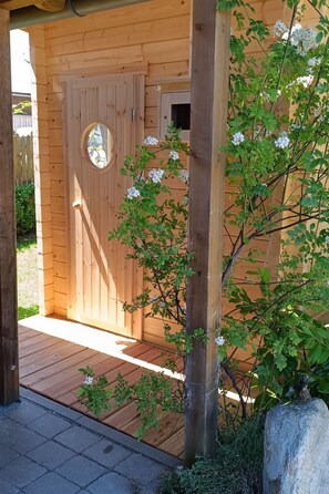 A wooden structure with a door and a small circular window, surrounded by greenery and a wooden deck. - Chalet  " Jagdhaus" by Interhome (Philippsreut)