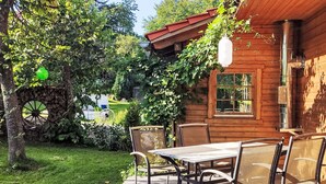 A wooden cabin with a patio, outdoor seating, and a stone wheel. - Chalet  " Jagdhaus" by Interhome (Philippsreut)