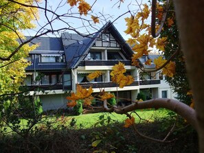 A two-story house with a dark roof and white walls, surrounded by autumn foliage. - Ferienwohnung mit Boxspringbett by Interhome (Goslar)