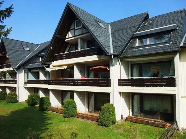 Eine Reihe moderner, zweigeschossiger Gebäude mit Balkonen und großen Fenstern, umgeben von gepflegten Rasenflächen und Hecken.