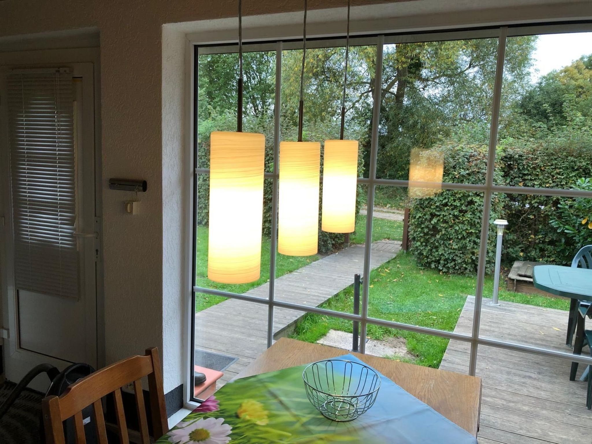 Uma sala de jantar com mesa, cadeiras e janela com vista para um jardim.