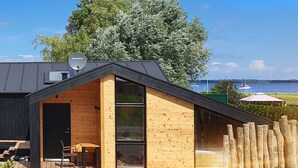 A modern cabin with a wooden exterior, a large glass door, and a deck area.