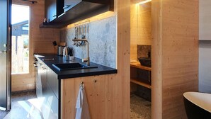 A modern kitchen with wooden walls, a black countertop, and stainless steel appliances.