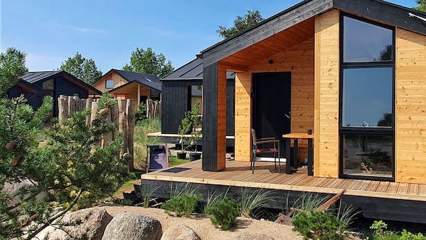 A modern wooden cabin with a deck, large windows, and a sign indicating a beer garden.