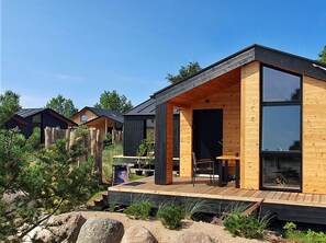 A modern wooden cabin with a deck, large windows, and a sign indicating a beer garden. - "Wolke 7" by Interhome (Boiensdorf)