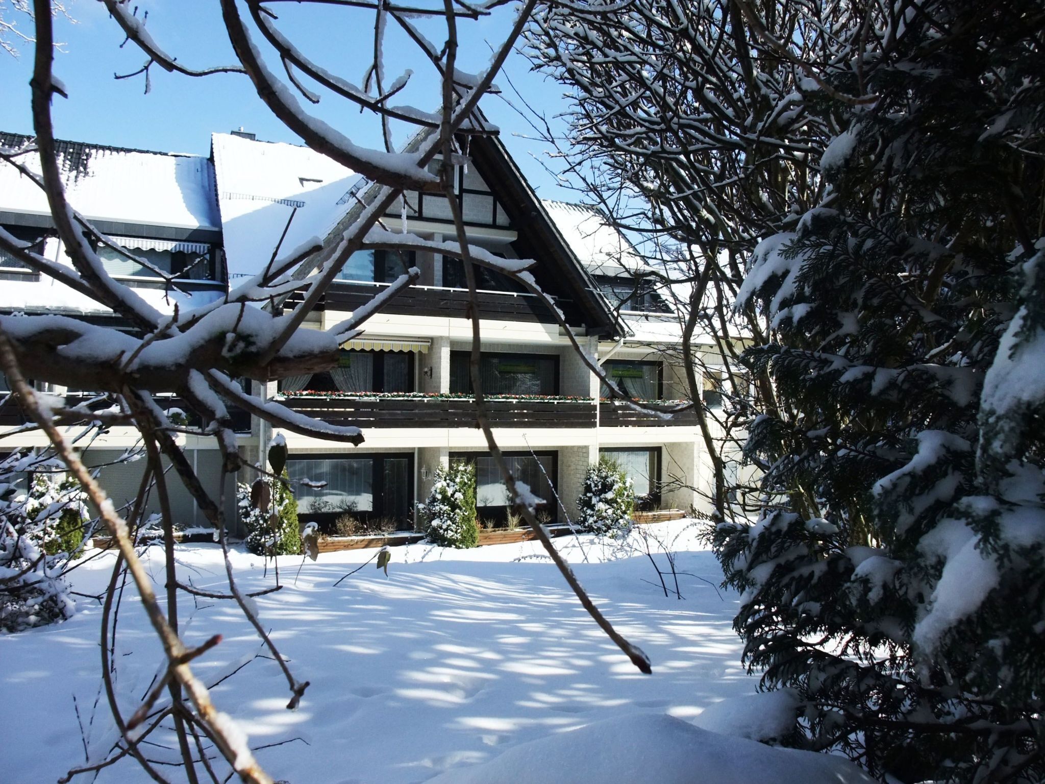 Um edifício com vários andares, telhado coberto de neve e varandas.