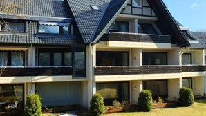 Una casa a due piani con tetto spiovente, ampie finestre e un piccolo balcone.