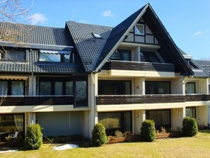 Ein zweistöckiges Haus mit geneigtem Dach, großen Fenstern und einem kleinen Balkon.