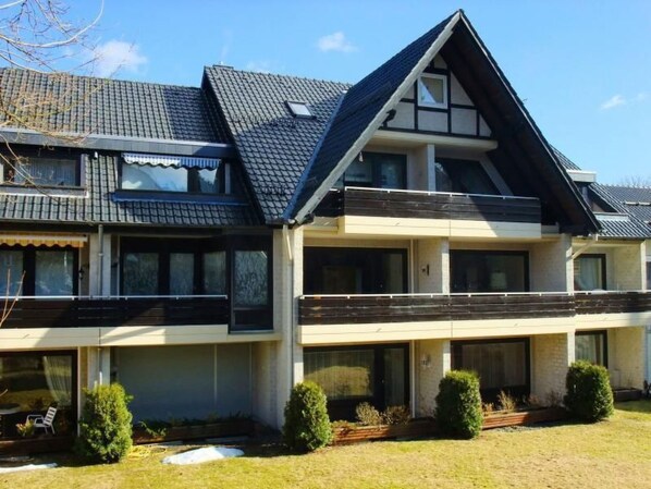 Ein zweistöckiges Haus mit geneigtem Dach, großen Fenstern und einem kleinen Balkon.