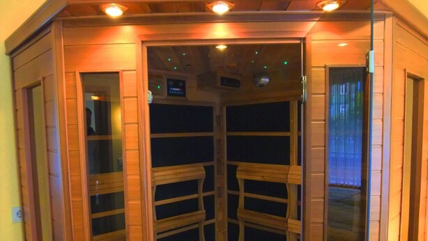 Una sauna con panche in legno e pareti in vetro, dotata di un pannello di controllo e asciugamani.