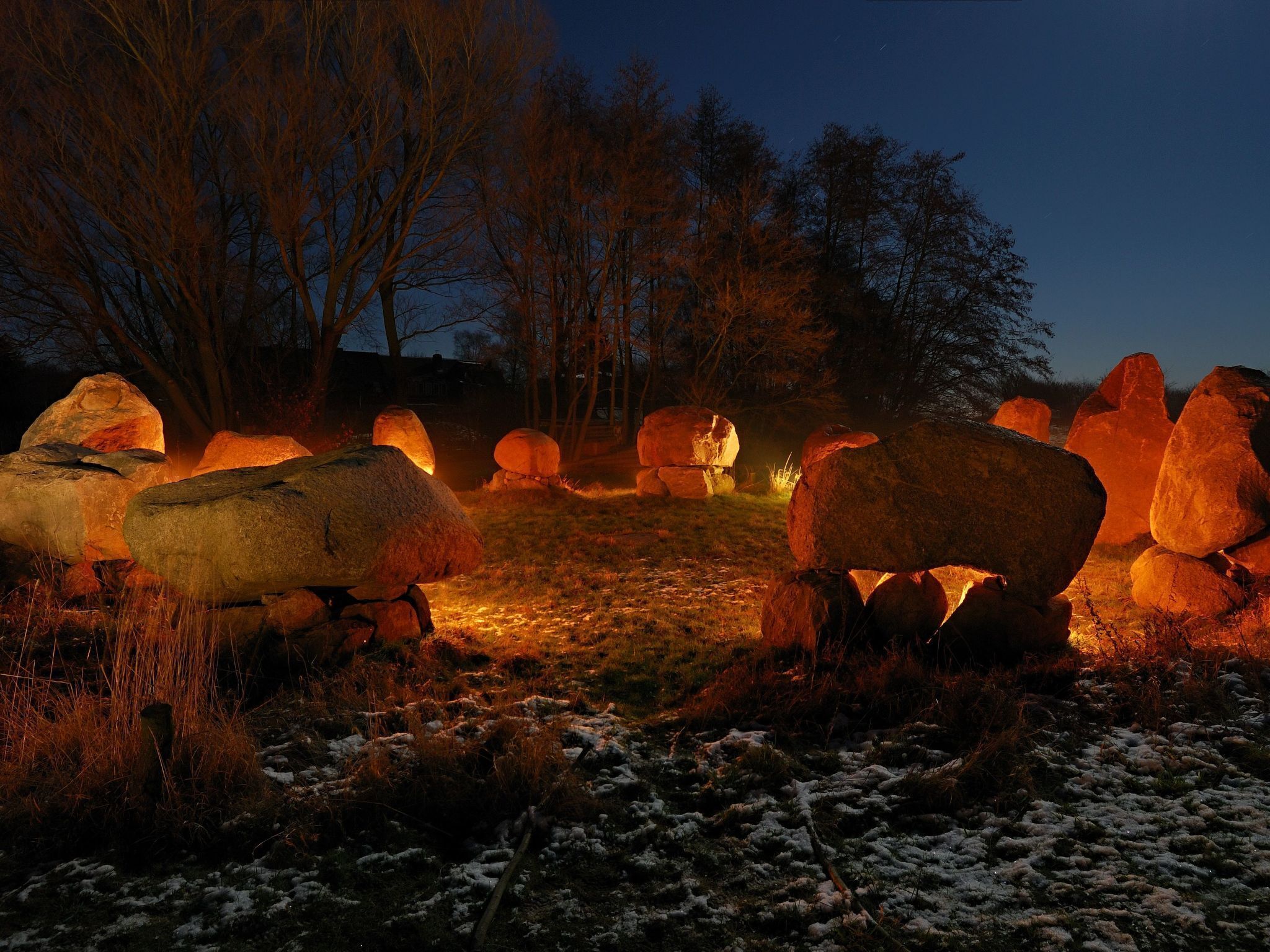 A nighttime outdoor setting with large rocks illuminated by artificial lighting.
