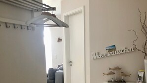 A modern kitchen with a white countertop, a hanging rack, and a door leading to a living area. - in Strandnähe by Interhome (Bad Doberan)