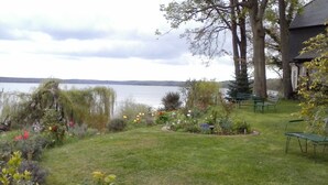 Un jardín con césped, bancos y vistas a un lago.