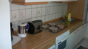 Een keuken met houten kastjes, een broodrooster, een waterkoker en een vaatwasser.