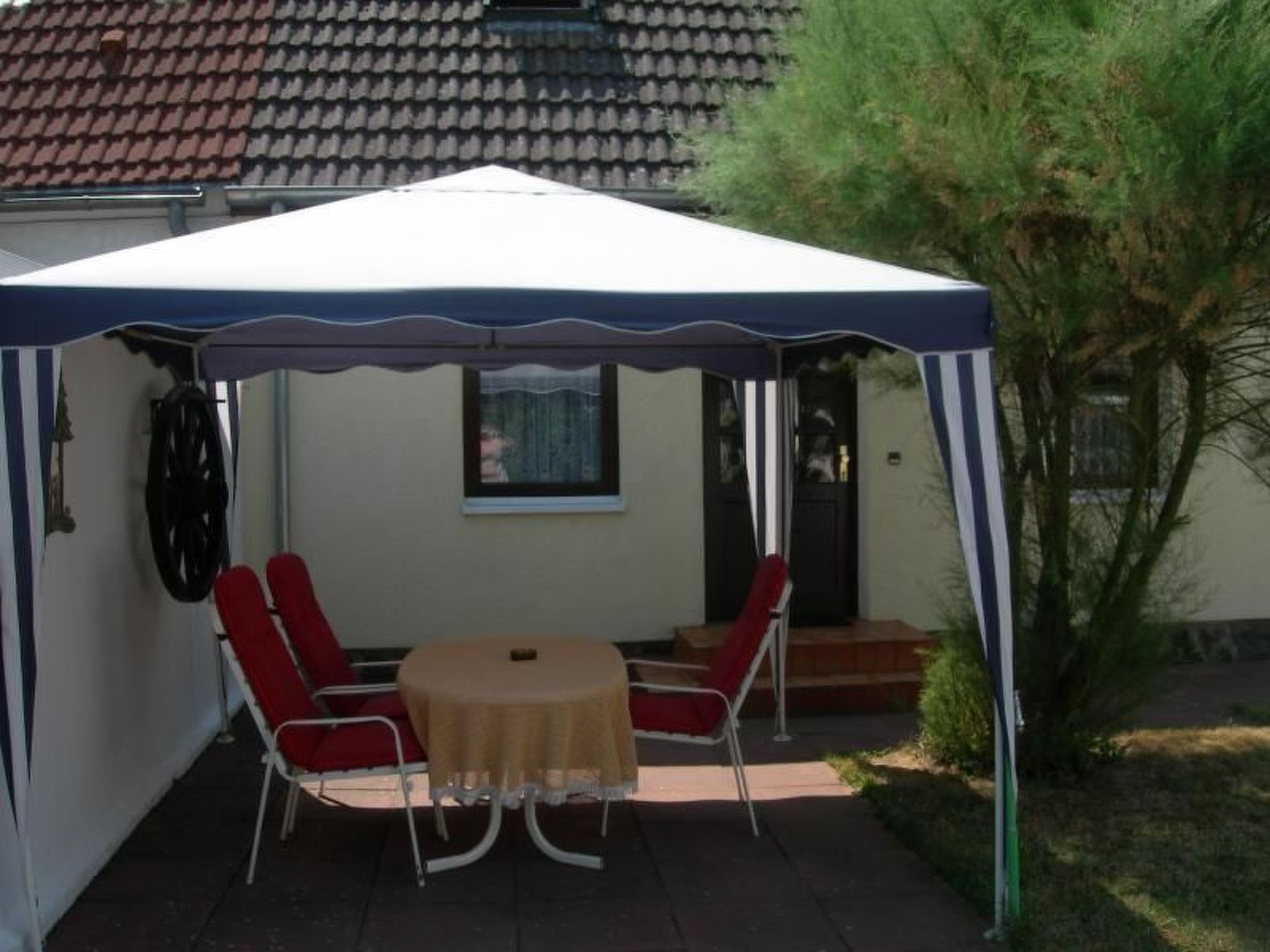 A covered patio with a table and chairs, a small window, and a door.