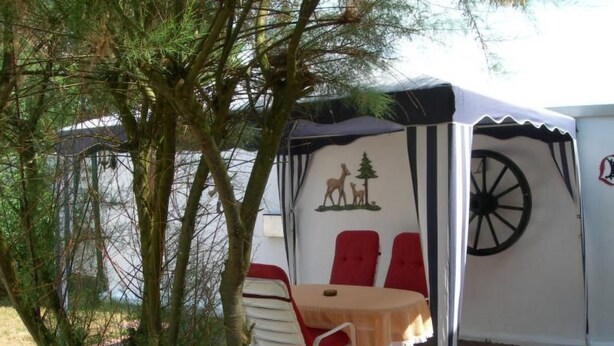Een tent met een tafel en twee rode stoelen, een wiel en een logo op de muur.