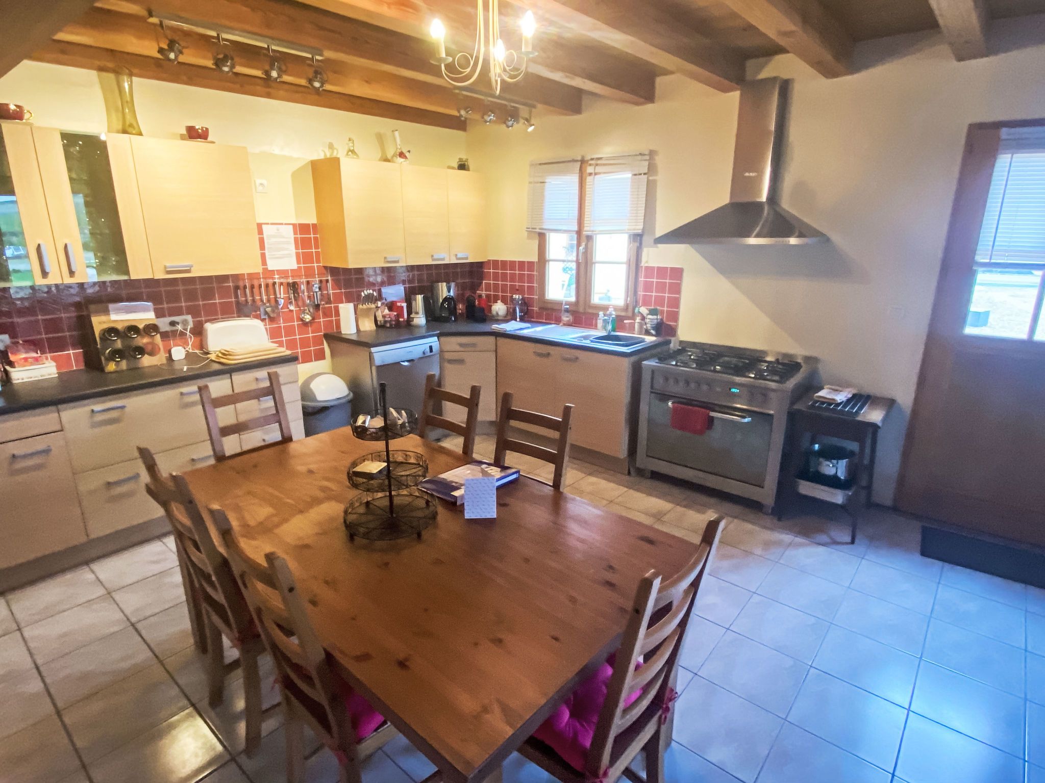A kitchen with a wooden dining table, chairs, a stove, and a window.