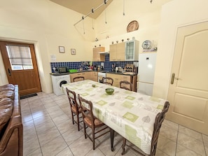 Cocina compacta con mesa, sillas, lavadora y refrigerador.