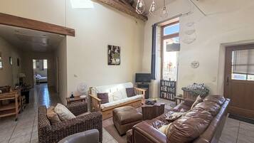 A spacious living room with a sofa set, a dining area, and a view of the outdoors.