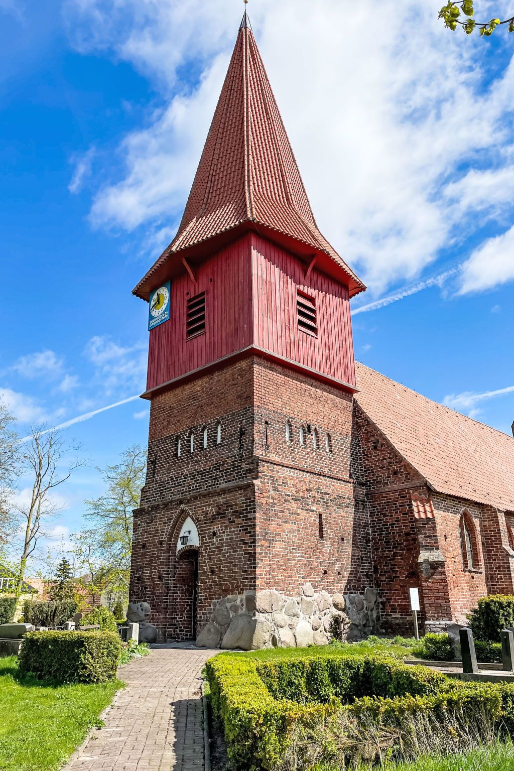 A red brick church with a tall tower and a clock.
