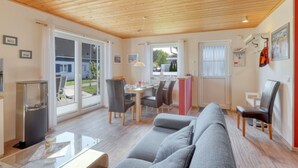 A modern living room with a wooden ceiling, a grey sofa, a dining area with a table and chairs, and a glass coffee table. - La Mer in Altefähr by Interhome (Seebad Altefähr)