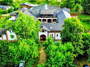 A large, multi-story building with a prominent central entrance, surrounded by lush greenery and trees.
