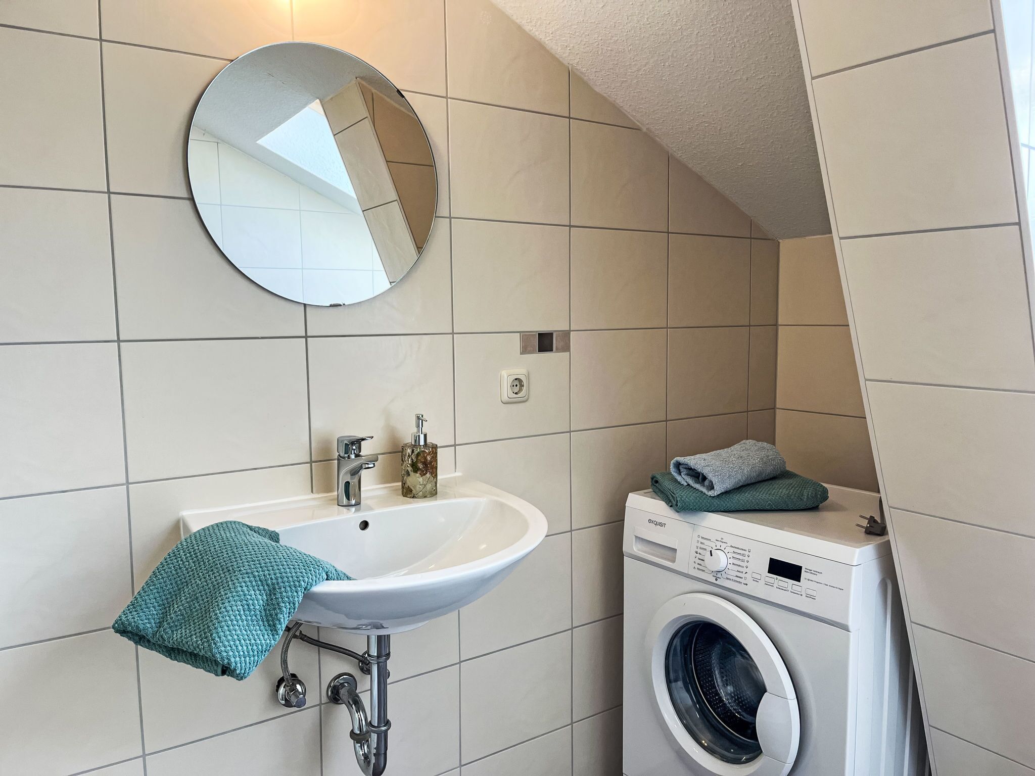 Ein Badezimmer mit Waschbecken, Spiegel und Waschmaschine.