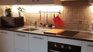 Une cuisine avec des meubles blancs, un four noir, un évier et un pare-feu.