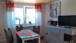 Un espace repas comprenant une table, des chaises, un téléviseur et un meuble.
