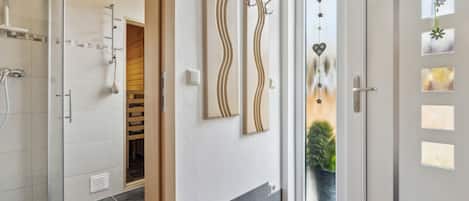 Un baño moderno con ducha, un perchero y una puerta con paneles de vidrio esmerilado.
