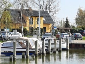 A marina with boats docked, a yellow building, and parked cars. - Ferienhaus-Bodden by Interhome (Neuendorf)