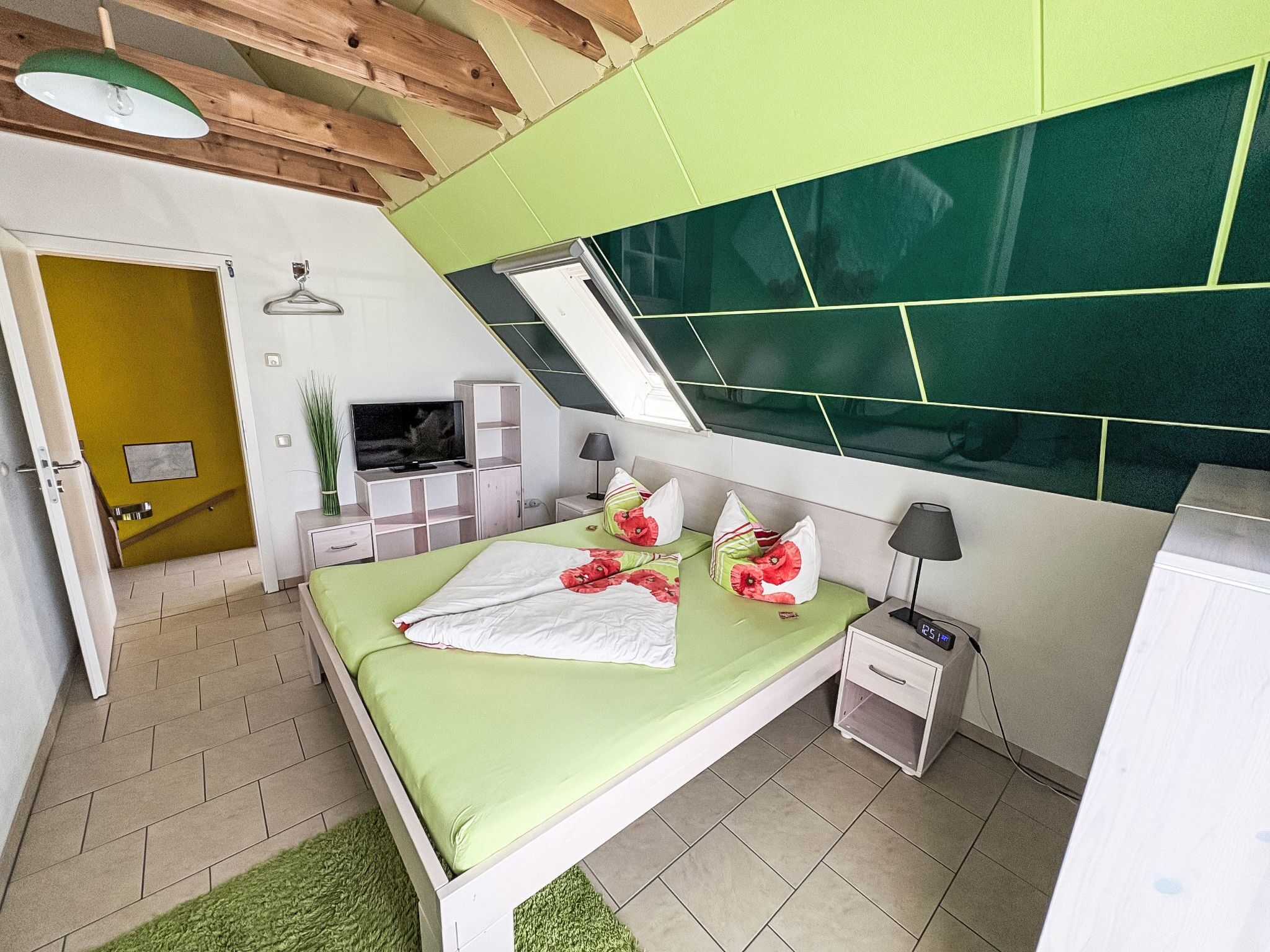 Een moderne slaapkamer met een bed, nachtkastjes, een lamp en een digitale klok.
