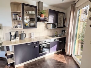 Una cucina moderna con forno integrato, microonde e lavandino. Si vede una finestra con vista sul verde.