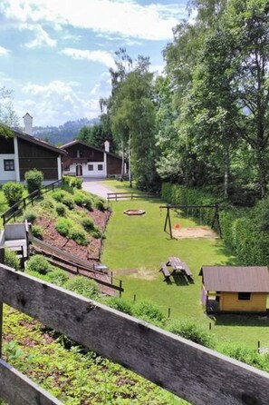 A residential area with a grassy lawn, a swing set, and a small yellow building. - Wohnung mit möblierter Terrasse und Waldblick by Interhome (Hauzenberg)