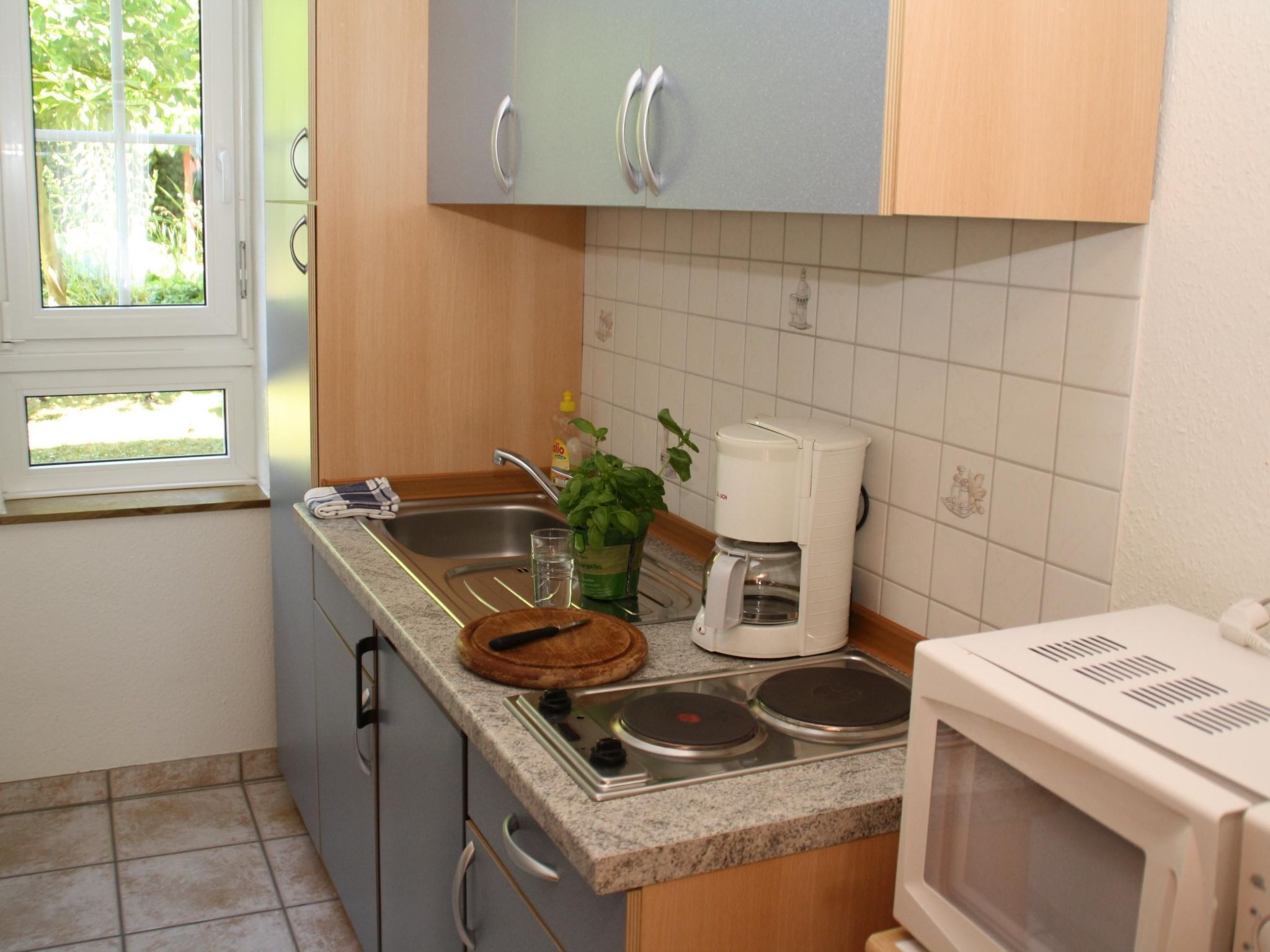 Una cucina accessoriata con lavello, fornelli, forno a microonde e macchina per il caffè.