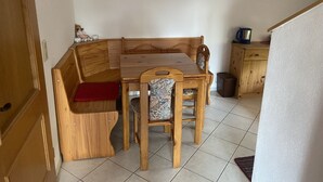 A wooden dining table with chairs, a bench, and a small cabinet with a kettle.