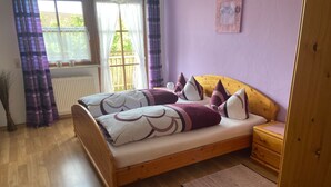 A bedroom with a wooden bed, a nightstand, a window with curtains, and a radiator.