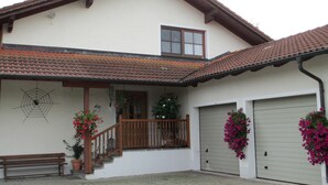 A two-story house with a tiled roof, a wooden balcony, and a garage.
