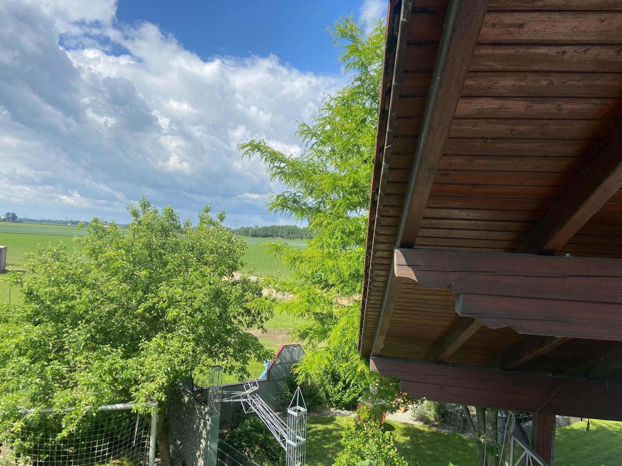 A wooden structure with a view of a green landscape and trees.