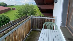 A balcony with a wooden railing, a table, and a chair. - Appartement Wimmer by Interhome (Bad Füssing)