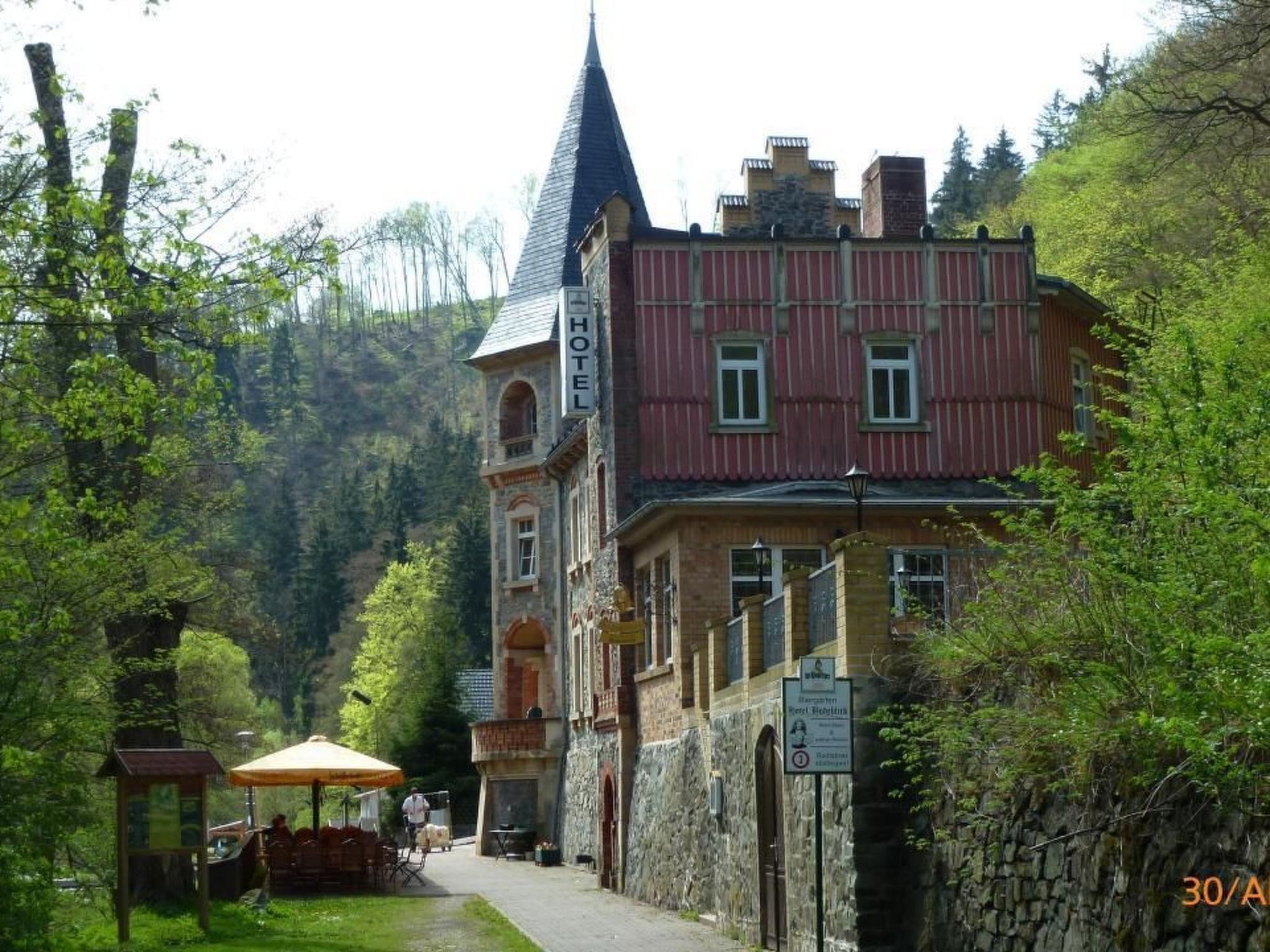 A hotel with a prominent tower, a red building, and a stone wall.