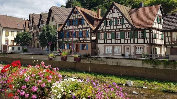 A row of traditional half-timbered houses with a river in the foreground. - Apartment Bär by Interhome (Baiersbronn)