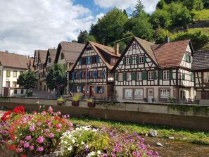 A row of traditional half-timbered houses with a river in the foreground. - Apartment Bär by Interhome (Baiersbronn)