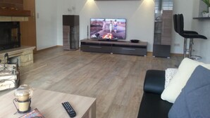 A modern living room with a fireplace, a flat-screen TV, and a bar area. - Waldperle by Interhome (Altwarp)