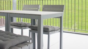 Een overdekt terras met een tafel en stoelen, met uitzicht op een groen veld.